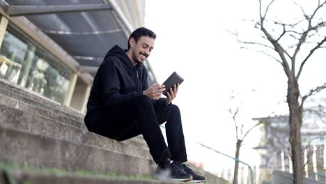 Smiling-young-man-with-tablet-computer-on-street
